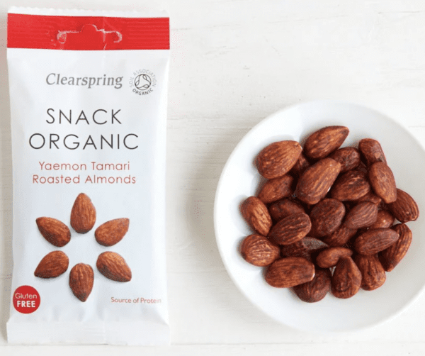 Packet of Clearspring Organic Tamari roasted Almonds 30g alongside saucer of approx 23 roasted almonds